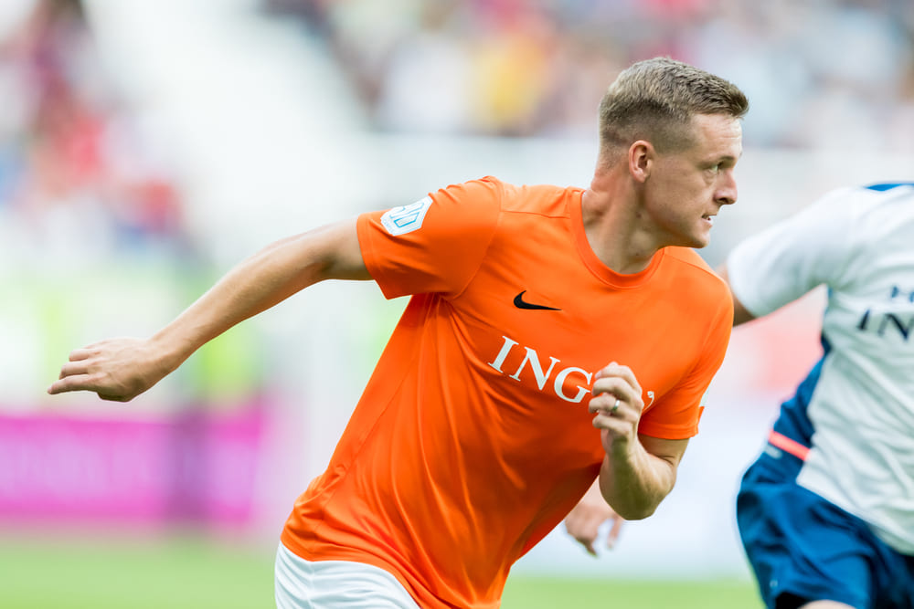 Felix Kroos in einem orangen Trikot auf dem Fußballplatz, welcher stark zu seinem Vermögen beigetragen hat.