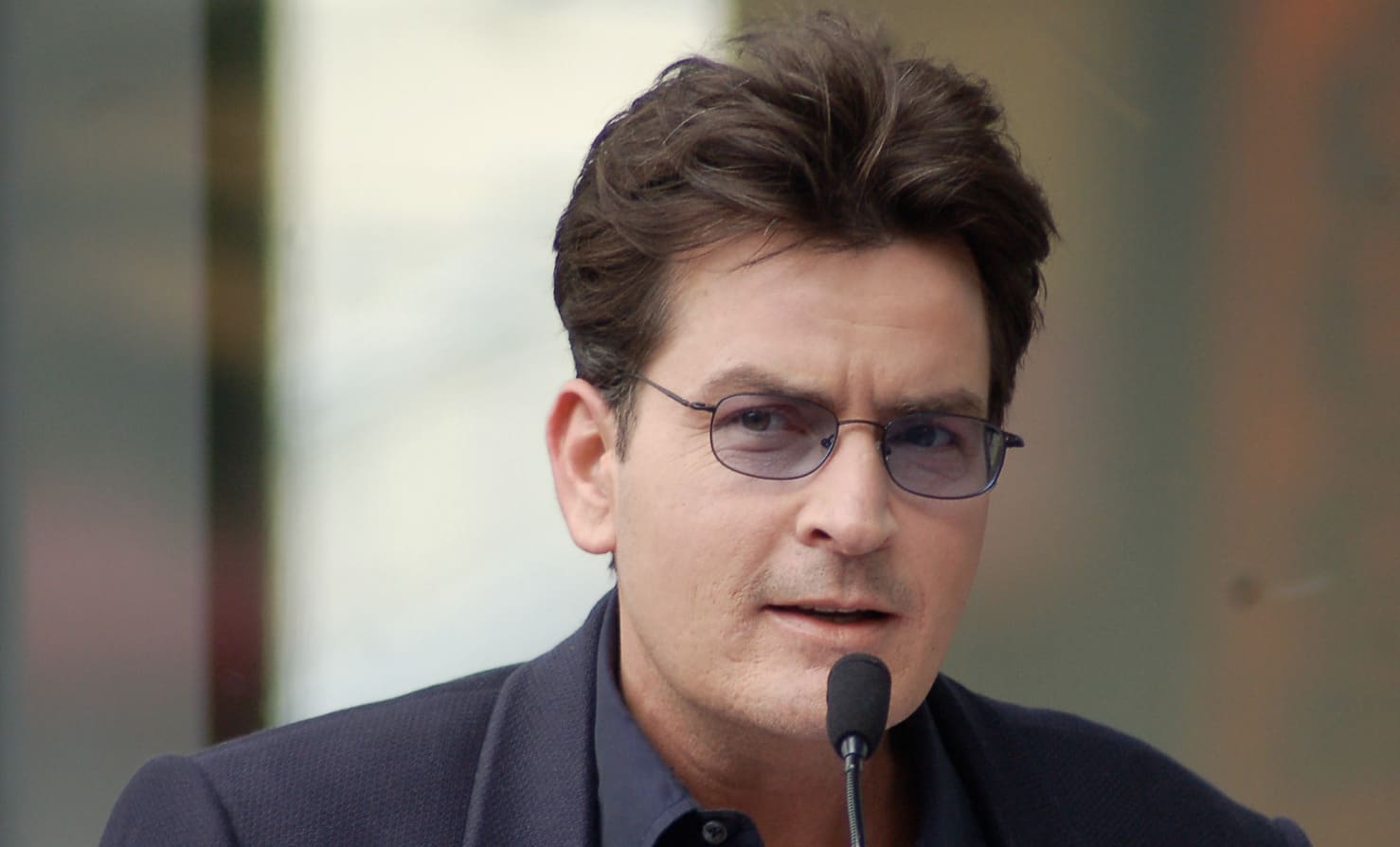 Charlie Sheen im Anzug und mit Sonnenbrille.